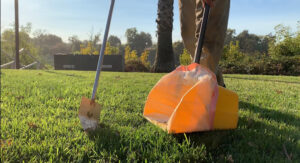 A Doo Doo Squad technician picking up dog poop in a yard